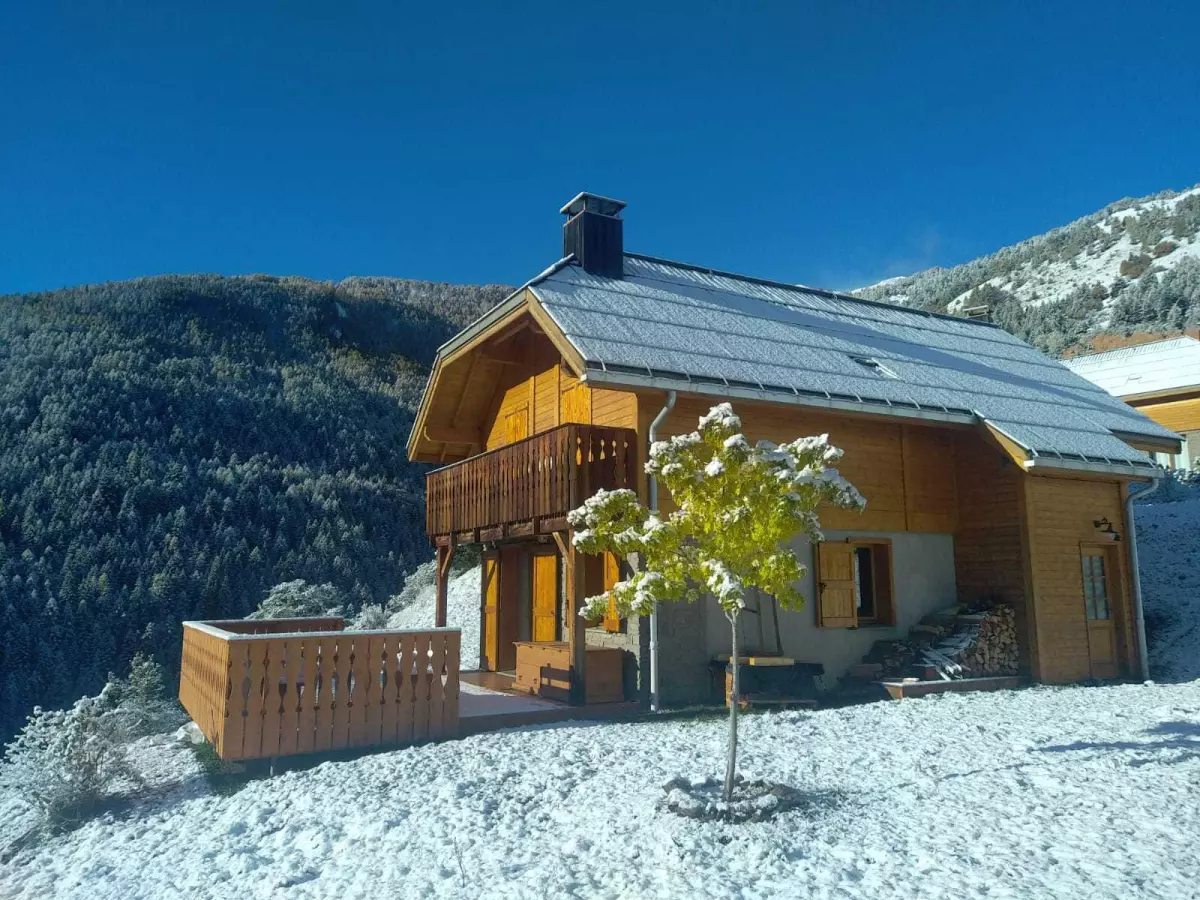 Chalet de montagne en bois sous la neige, niché au cœur des Alpes, idéal pour un séjour hivernal au calme avec vue sur la forêt.