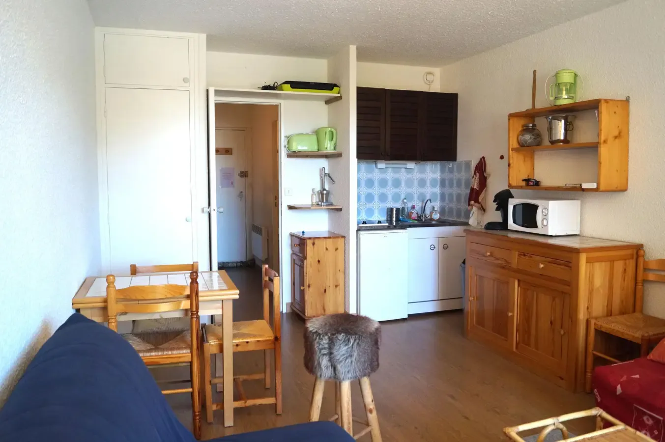 Séjour de studio chaleureux avec coin cuisine rustique, mobilier en bois et espace repas convivial pour des vacances à la montagne.
