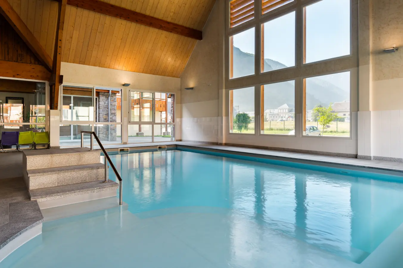 Piscine intérieure de la résidence Le Belvédère avec grandes baies vitrées offrant une vue sur les montagnes environnantes.