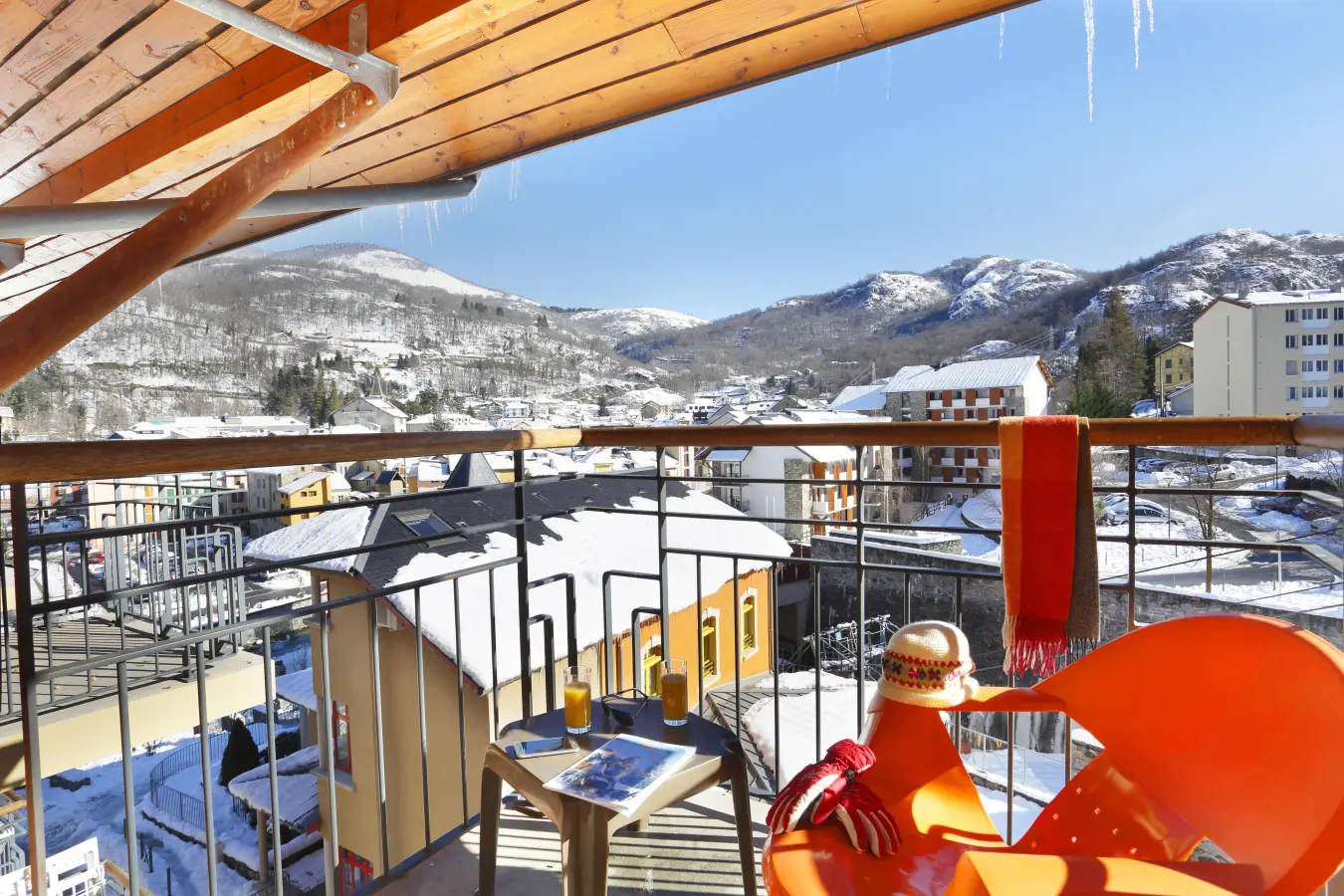 Vue depuis le balcon d’un appartement de la résidence Les Grands Ax, sur le village enneigé et les montagnes environnantes.
