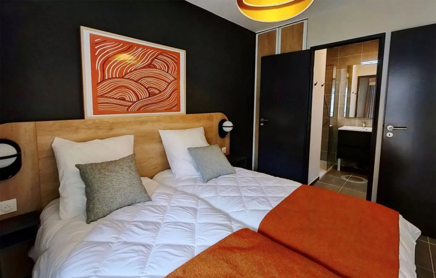 Chambre moderne et élégante avec deux lits simples, tête de lit en bois, décoration design et salle de bain attenante.